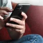 Jugendlicher versendet SMS mit iPhone.