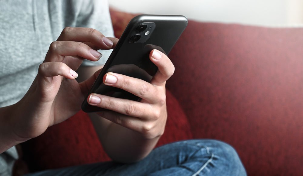 Jugendlicher versendet SMS mit iPhone.