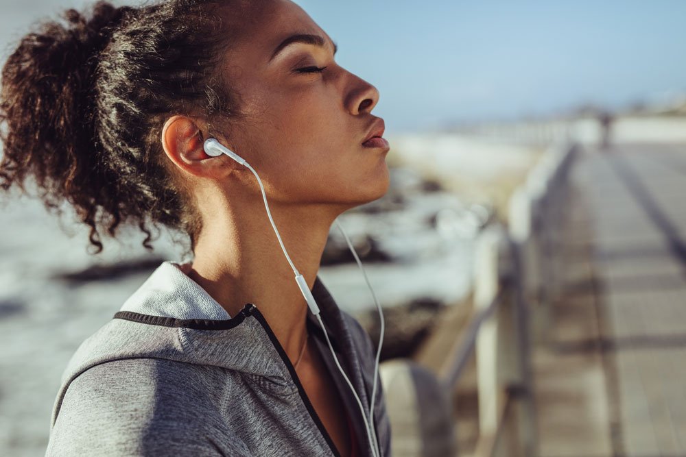 Frau hört mit In-Ear Kopfhörern Musik.