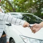 Privater Autoverküfer übergibt Autoschlüssel.