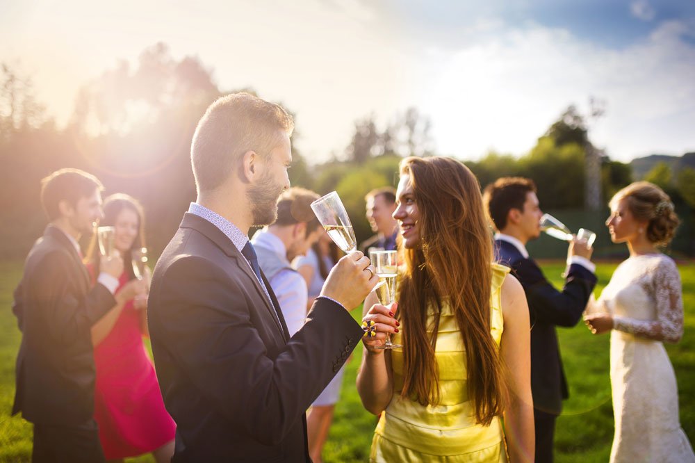 Passend gekleidete Hochzeitsgäste trinken Champagner.