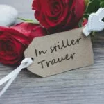 Trauerkarte "In stiller Trauer" vor roten Rosen.
