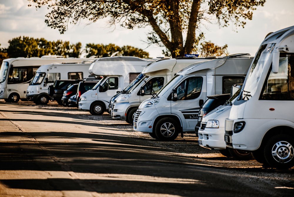 Verschiedene Wohnmobile und Caravans parken an der Straße.