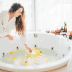 Junge Frau im Bademantel, die das Wasser im Whirlpool berührt.